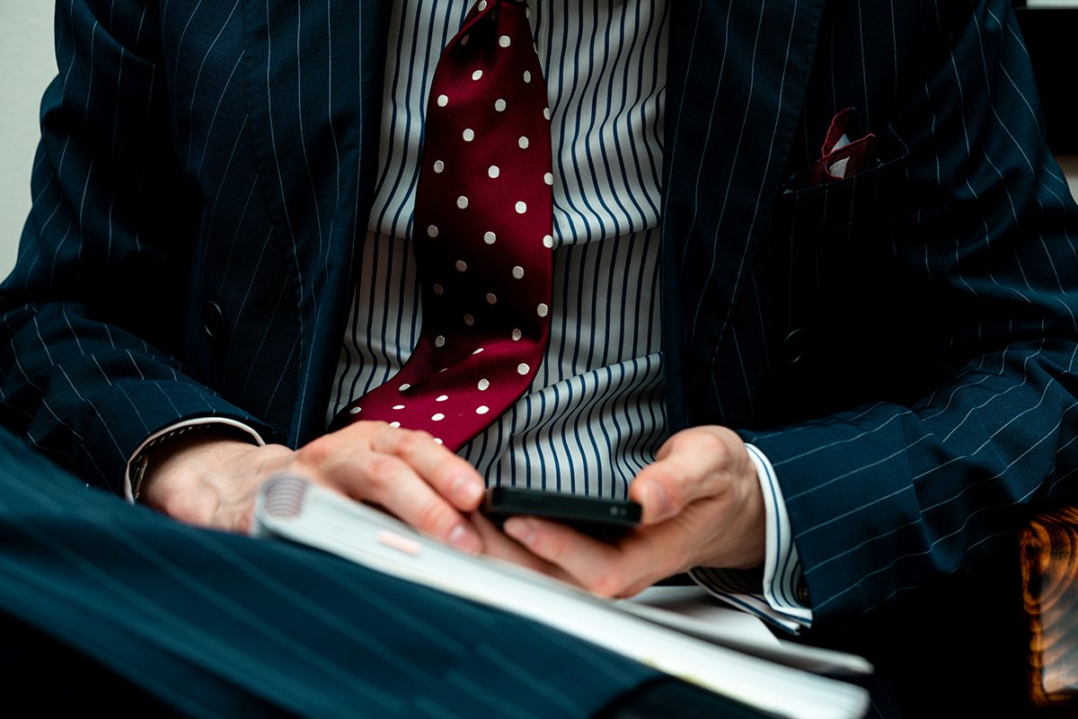 An adviser in a tailored suit reviewing notes on a phone