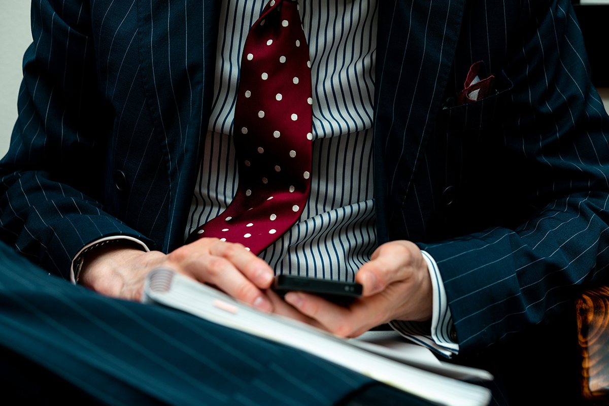 An adviser in a tailored suit reviewing notes on a phone